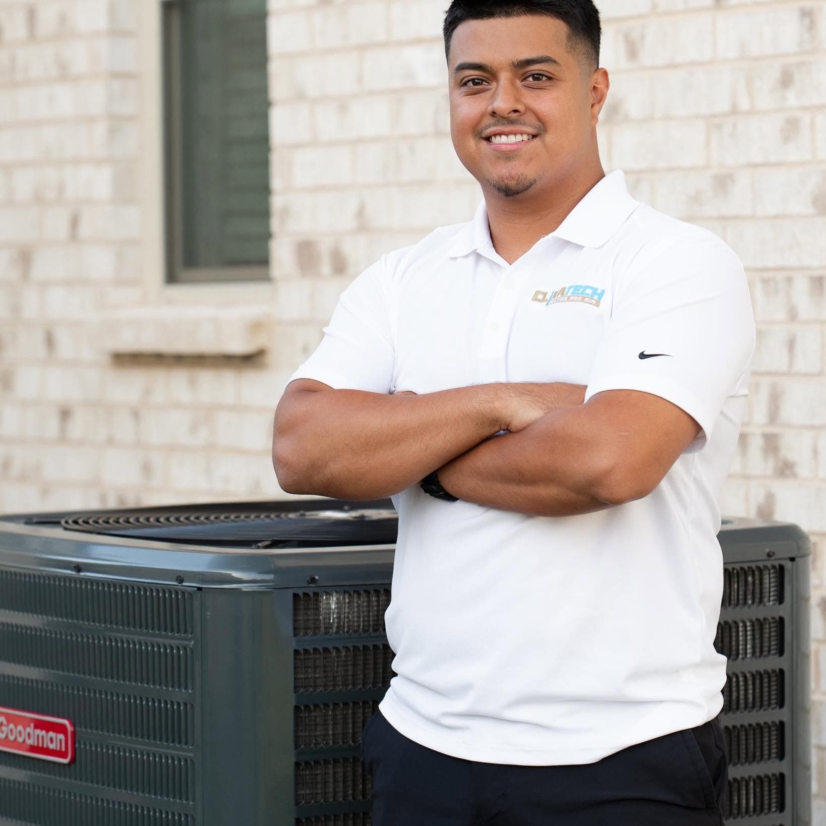 The owner of Climatech Heating and Air beside a Goodman condenser he installed